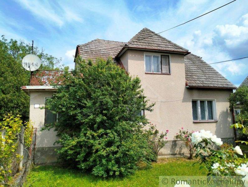 A family house in Košeca surrounded by greenery, with a simple facade and a satellite dish.