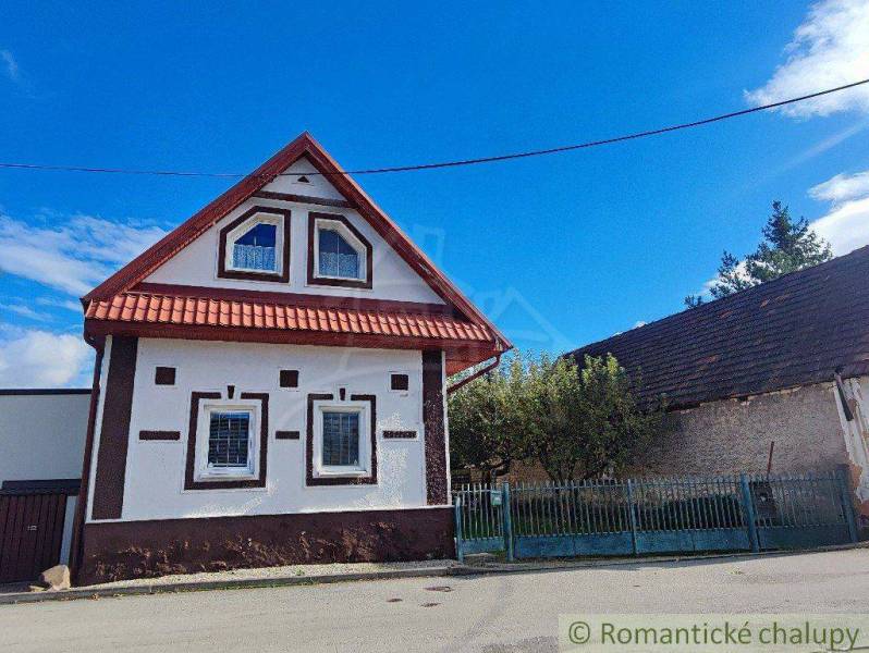 Traditional family house with a wooden roof and typical windows, street, fence, sky.