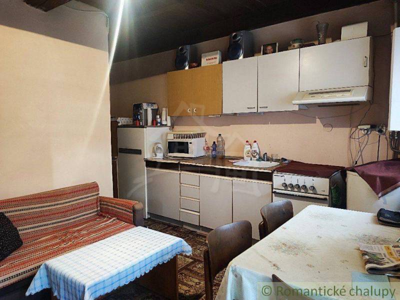 A kitchen in a family house with a kitchen unit, refrigerator, sofa, and table.