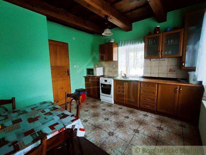 The interior of a cottage with green walls, a kitchen, and wooden furniture, ideal for a family home.