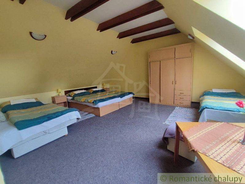 An attic room in a family house with beds, a wardrobe, and a window in the slanted ceiling.