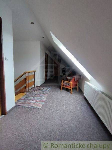 Attic hallway in a family house with a staircase, chair, and radiator.