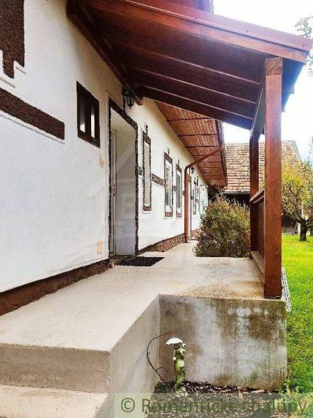 Traditional house with a wooden roof and entrance, view of the yard with a lawn.