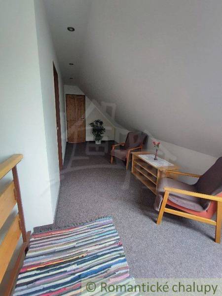 Attic space with chairs, a table, wooden elements, and a carpet in a family house.