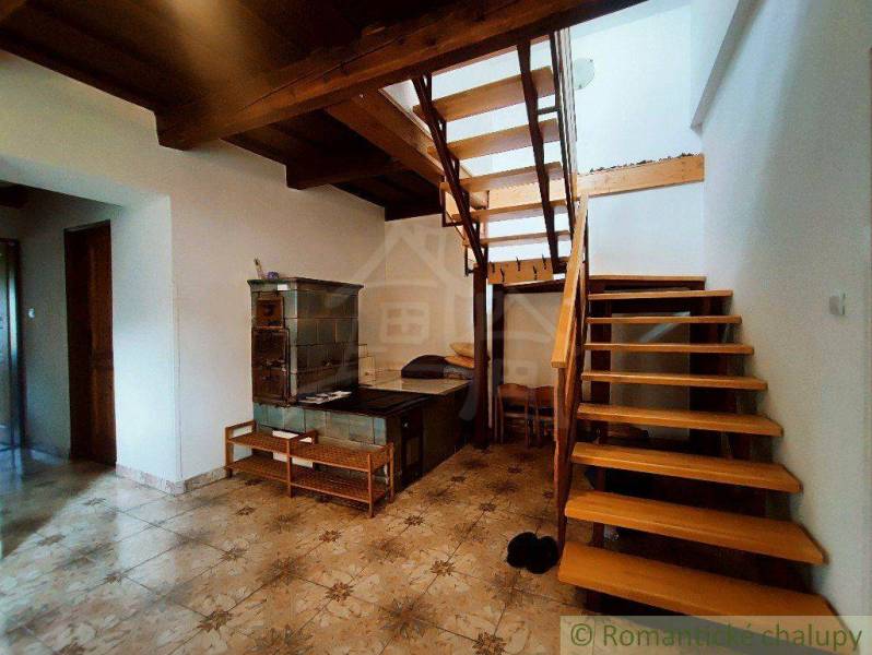The interior shows a rustic stove, wooden stairs, and paneling in a family house.