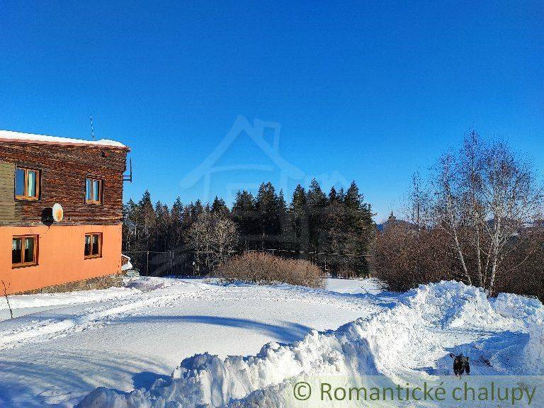 A snowy plot with a cottage surrounded by nature and a view of the forest: family house.