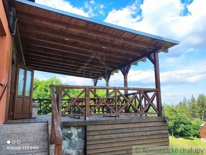 A wooden terrace, attached to a family house, with a view of nature and the forest.
