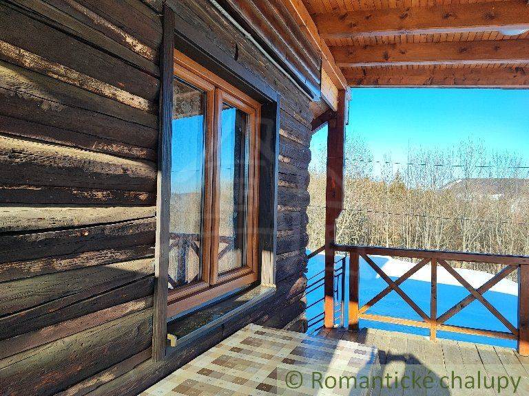 Wooden cottage with a spacious veranda, view of the snowy landscape, family house for sale.