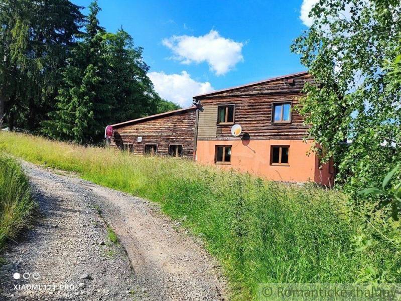 A country house with wooden elements, surrounded by nature and greenery.