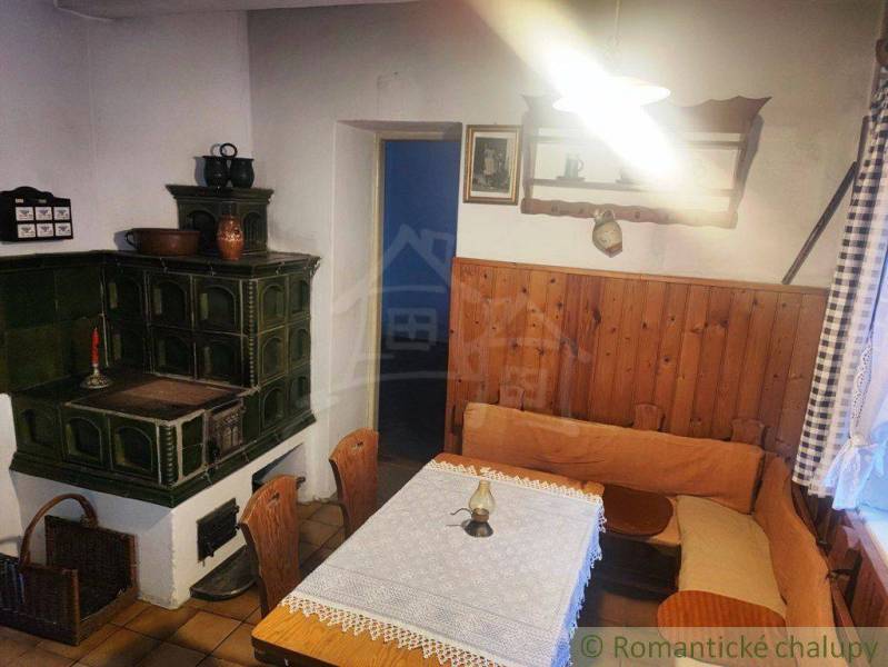Traditional kitchen with a tiled stove, wooden paneling, and rustic furniture in a family house.