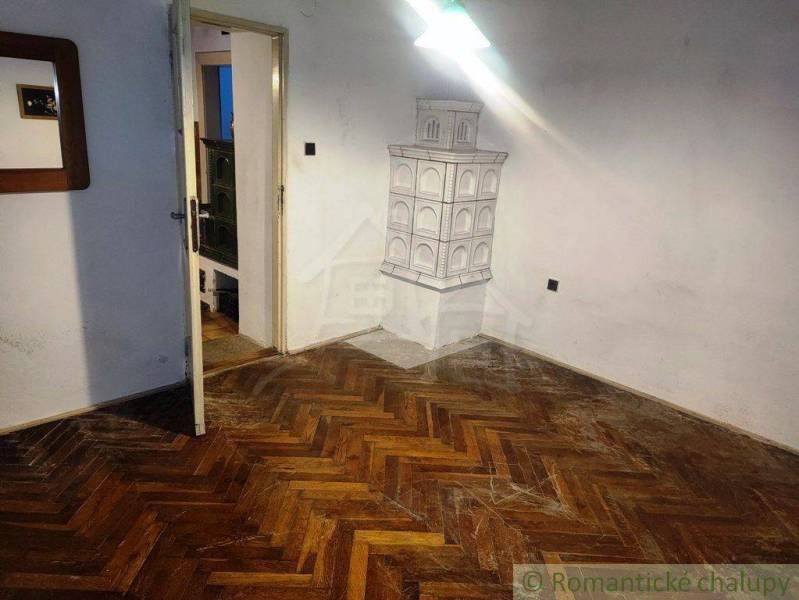 A room with a parquet floor, doors, a fireplace stove, and a mirror within a family house.