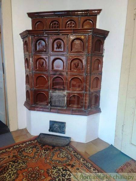 Traditional tiled stove on a red carpet in the living room of a family house.