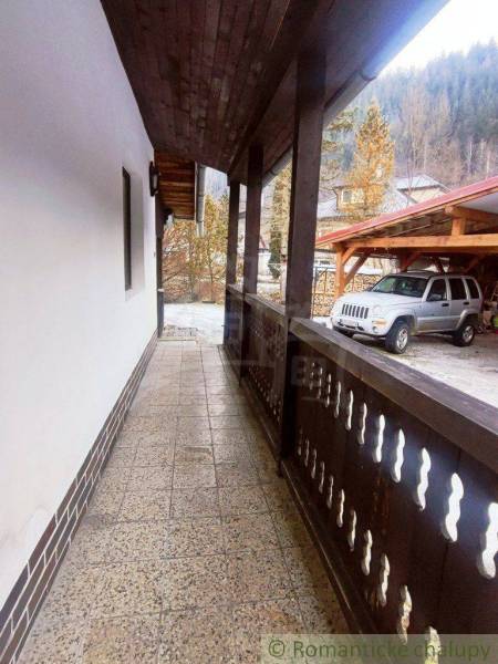 Entrance with a porch and adjacent parking at a family house in a mountain setting.