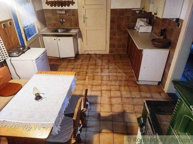 A kitchen in a family house with a tiled stove and a wooden table with a lace tablecloth.
