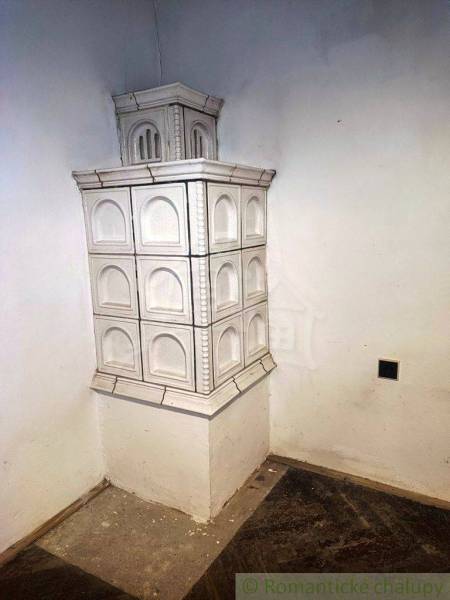 A white tiled stove in the corner of a family house with a wooden floor.