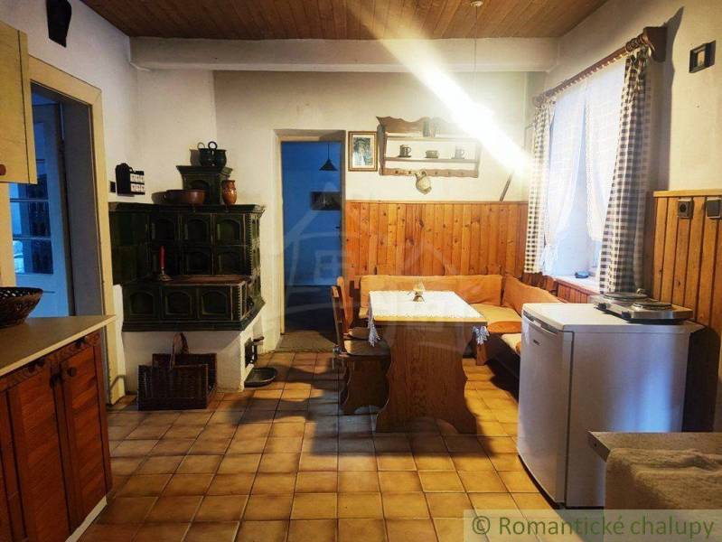 Country kitchen with a tiled stove, wooden paneling, and a corner bench for a family house.