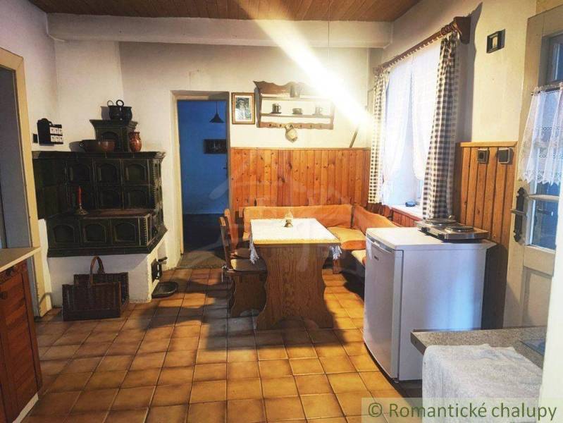 A country kitchen with a stove, wooden furniture, and a tiled stove in a family house.