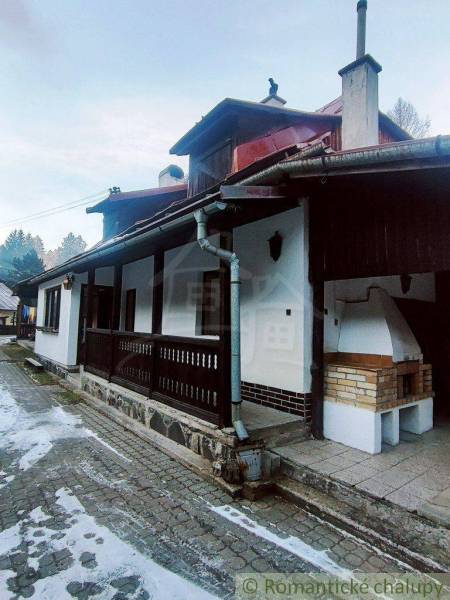 A family house with a wooden terrace and an outdoor grill surrounded by nature in winter.