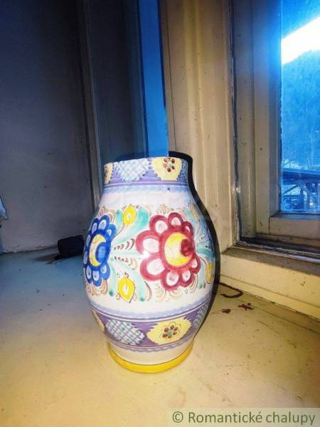 A colorful ceramic vase with floral patterns on the windowsill of a family house.