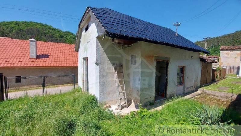 A small family house with a garden, grass, and surroundings in a mountainous landscape.