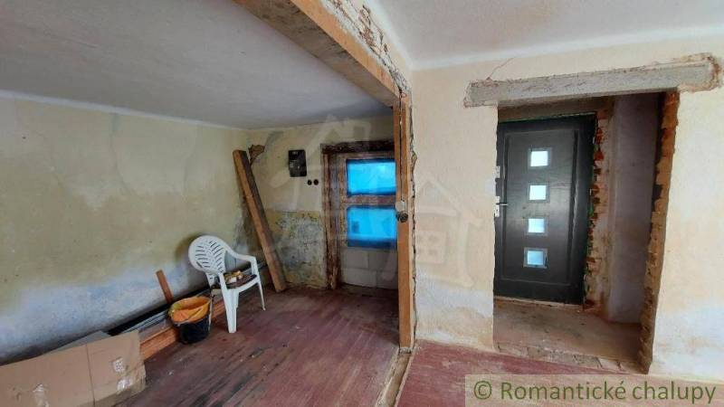 Interior of a family house under renovation with an entrance door and a plastic chair.