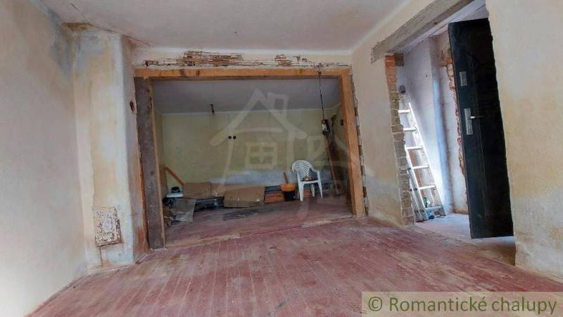 Room under renovation, described Family house with a chair, ladder, bucket, and a large wall.