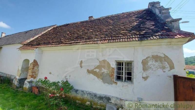 An old family house with a tiled roof, surrounded by nature and a lawn.
