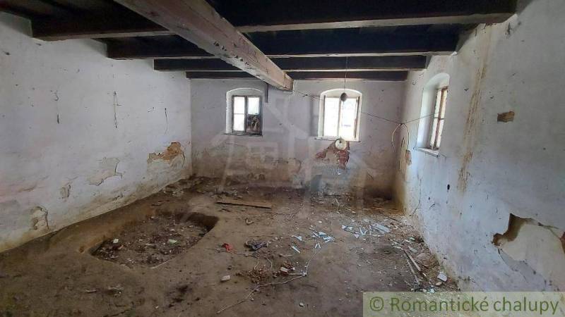 An abandoned room with wooden beams, a broken wall, located in an old family house.