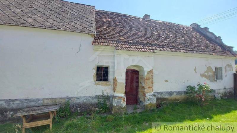Old family house with peeling plaster, wooden table next to the house.