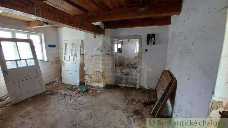 A room with leaky walls and wooden beams in a family house for renovation.