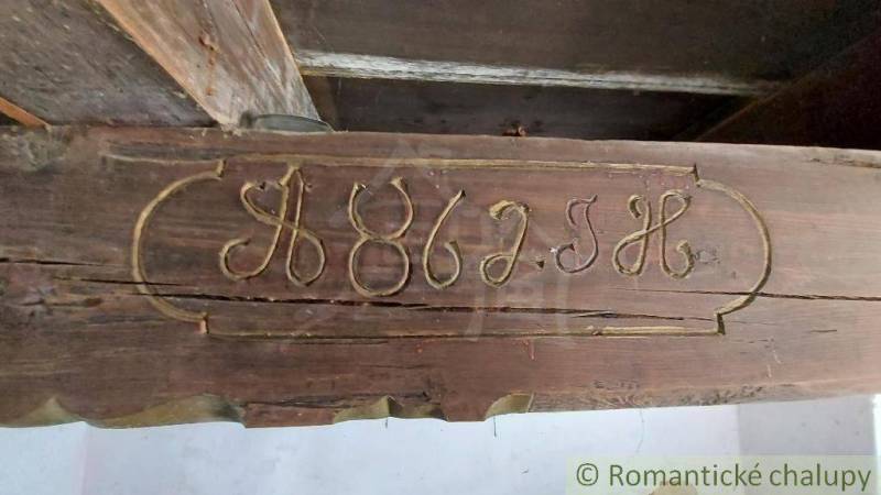 Carved inscription on a wooden beam, part of a historic family house, preserves authenticity.