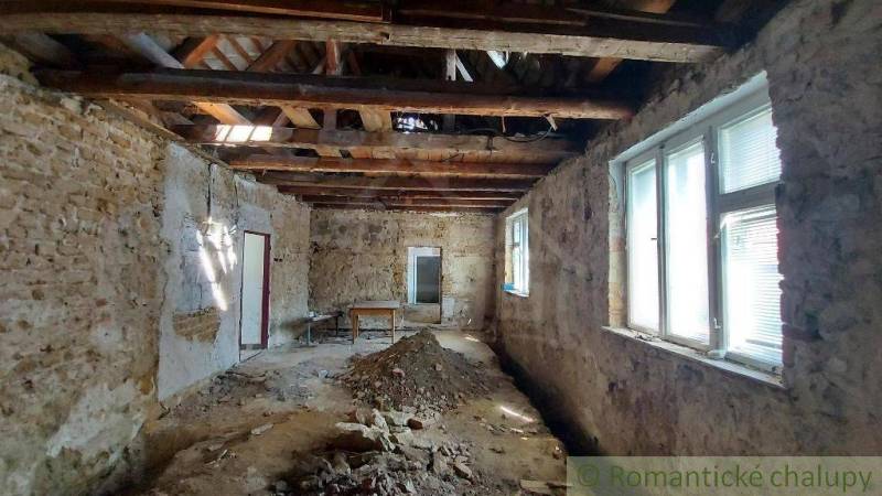 Interior of a family house with old brick walls, exposed ceiling, and windows.