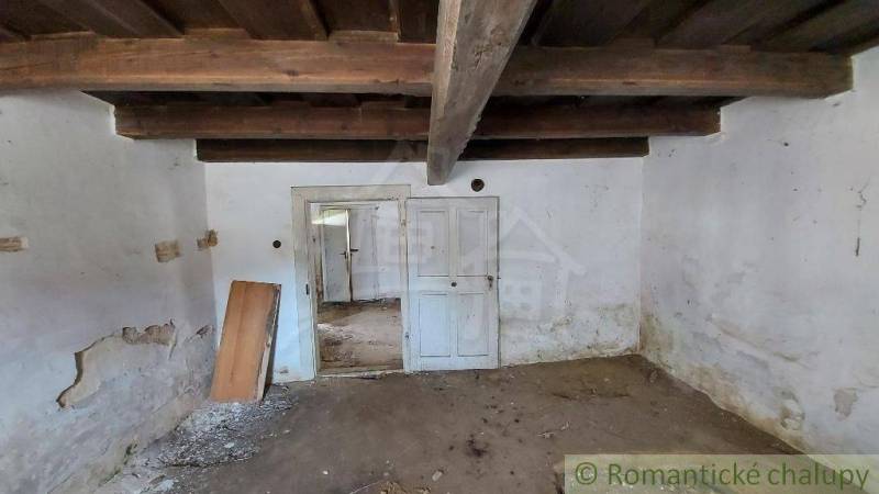 An old family house with a wooden ceiling, doors, and peeling plaster in the attic space.