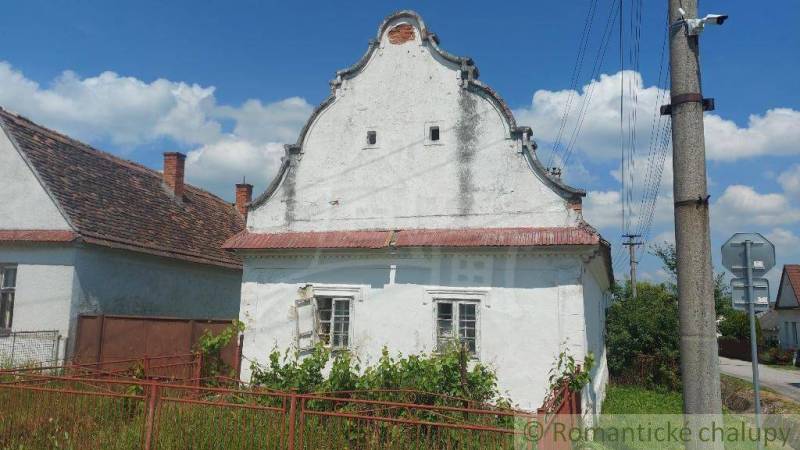A historic family house with an old roof and fence in the countryside on a sunny day.