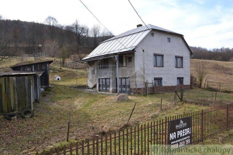 The family house stands on a sloped plot, surrounded by a garden and farm buildings.