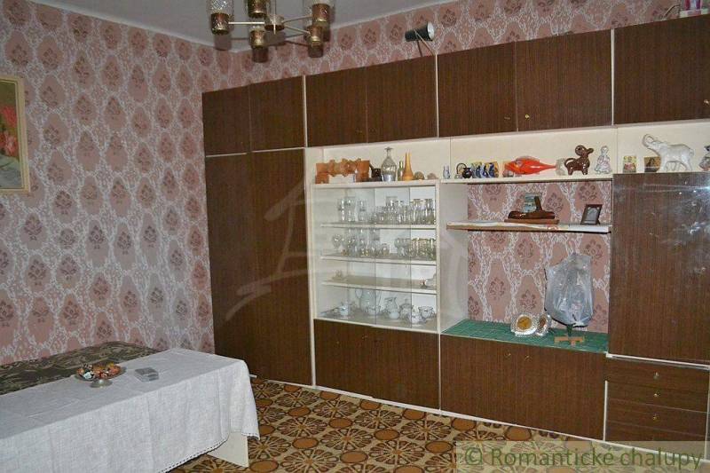 A retro living room with wallpaper, a wardrobe, a display cabinet, decorations, and a family house create a cozy interior.