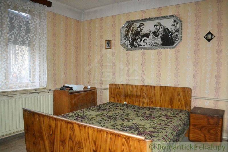 A bedroom in a family house with retro wallpaper, wooden furniture, and wall decorations.