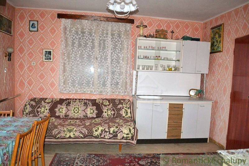 A room in a family house with a sofa, a wardrobe, and floral-patterned curtains.
