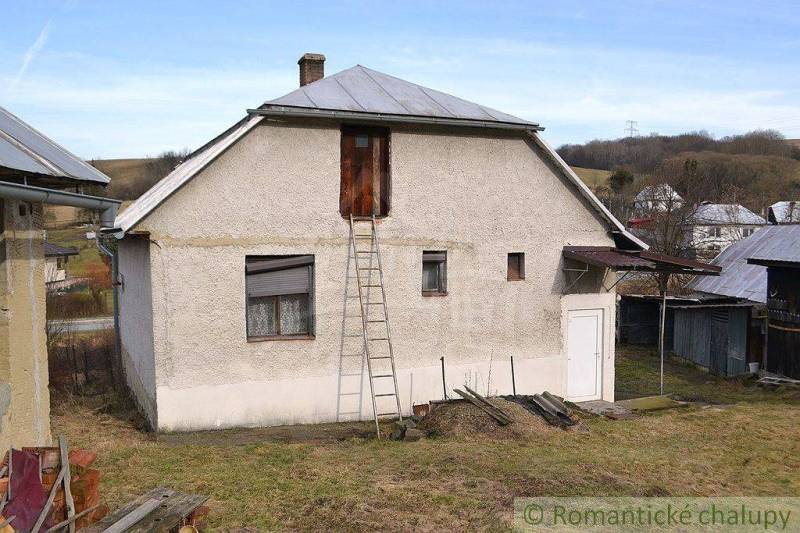 A family house with a white facade, metal roof, gardens around, a beautiful cottage.