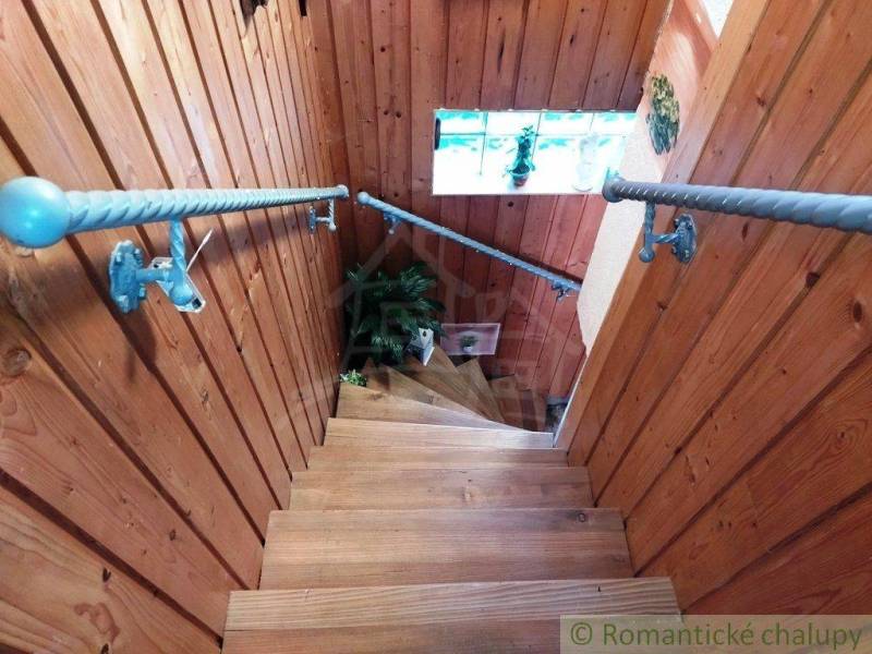 Wooden staircase with blue railing in a cozy family house, flowers on the windowsill.