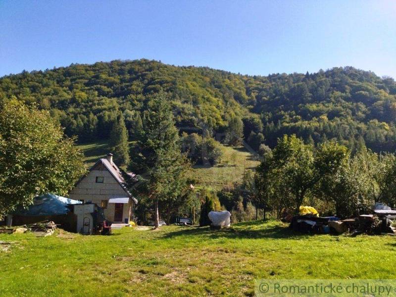 A family house in a quiet nature, surrounded by trees, with hilly landscape in the background.
