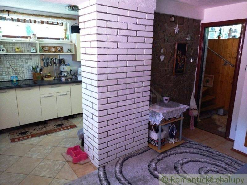 Interior of a family house, kitchen with white bricks, stone wall, and stairs in the background.