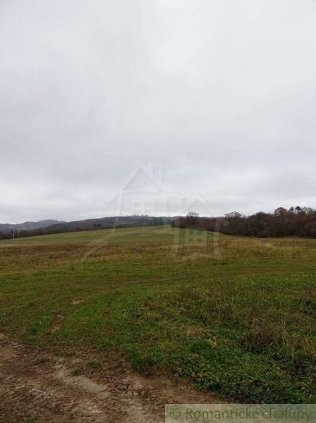 Vast fields and forest lands on gently rolling terrain under a cloudy sky.