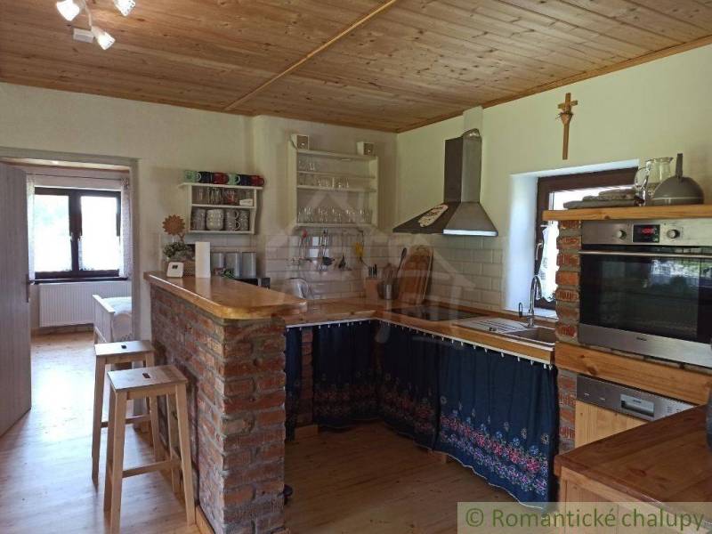 A kitchen with a wooden ceiling, a brick counter, complemented by equipment suitable for a cabin.
