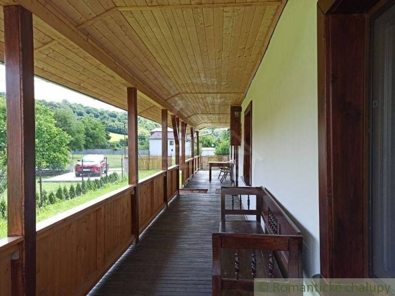 A long wooden porch at the cottage, overlooking the garden and surrounding hills.