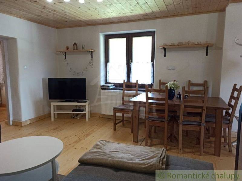 Rustic cottage with wooden ceiling, furniture, and television, providing a cozy space for relaxation.