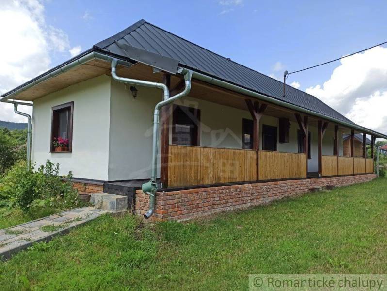 I see a traditional cottage with a wooden porch and an elevated brick foundation.