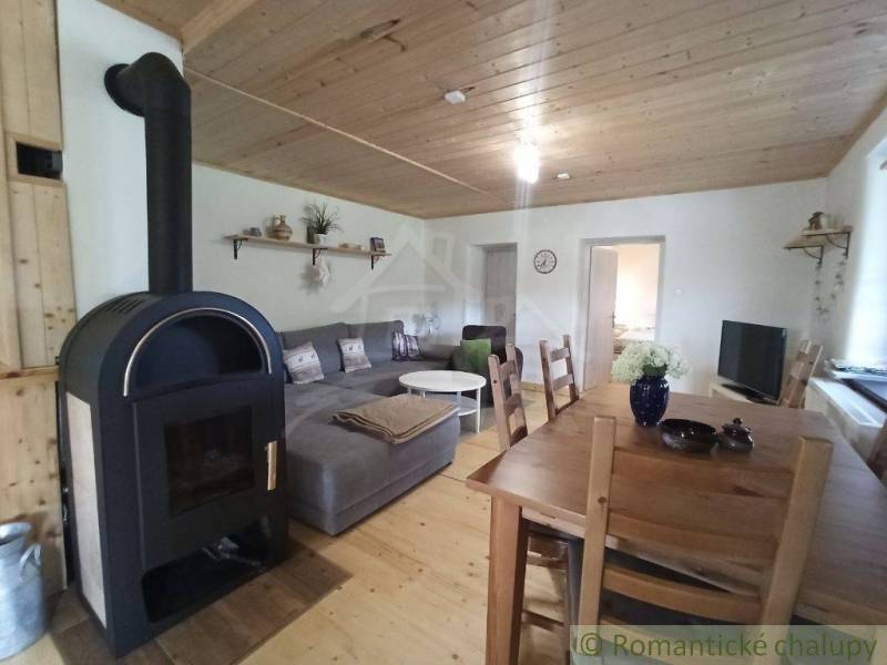 The interior of a cabin with a fireplace, wooden ceilings, a cozy sofa, and a dining table.