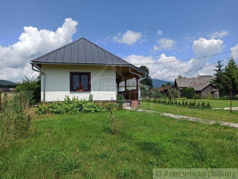 A village cottage with a tin roof, rustic style, beautiful garden, and surrounding nature.