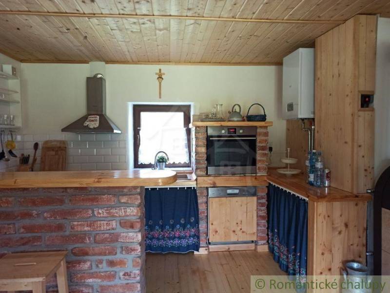 Rustic kitchen with a brick counter in the interior of a cottage, wooden elements, and a stove.